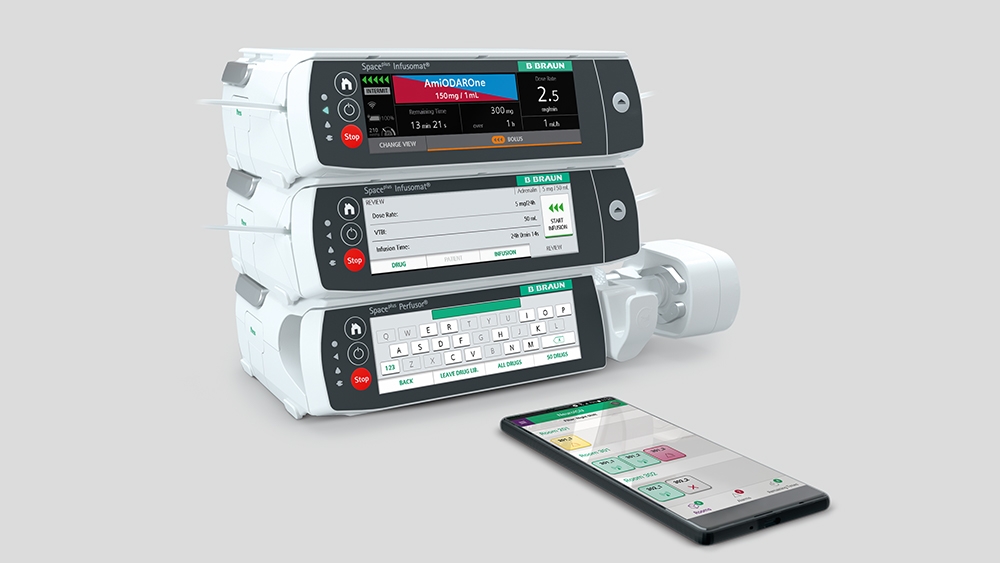 Space Plus Infusion System og en smarttelefon som ligger foran det med den tilhørende appen åpen. 