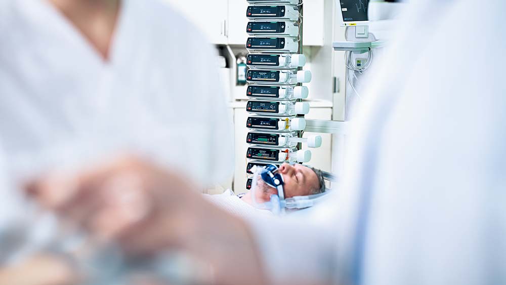 Pasienten ligger på en intensivavdeling – det er mange B. Braun infusjonspumper i bakgrunnen
