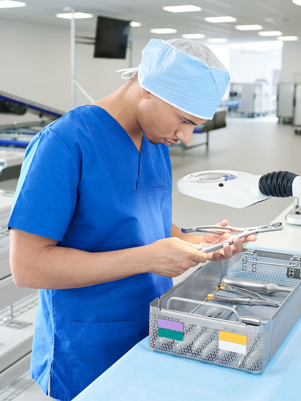 Ansatt ved sterilsentralen kontrollerer ulike instrumenter i en rist