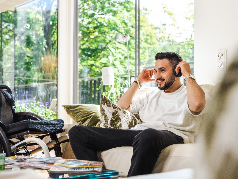 mann på sofa i privat stue med hodetelefoner på hodet, slapper av 
